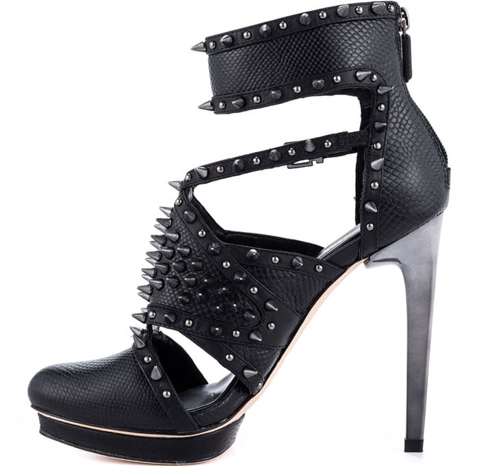 BCBGMAXAZRIA “Hersh” spiked pumps in black leather, featuring studded straps, ankle cuffs, and towering metallic heels that bring edge and structure to an all-black look