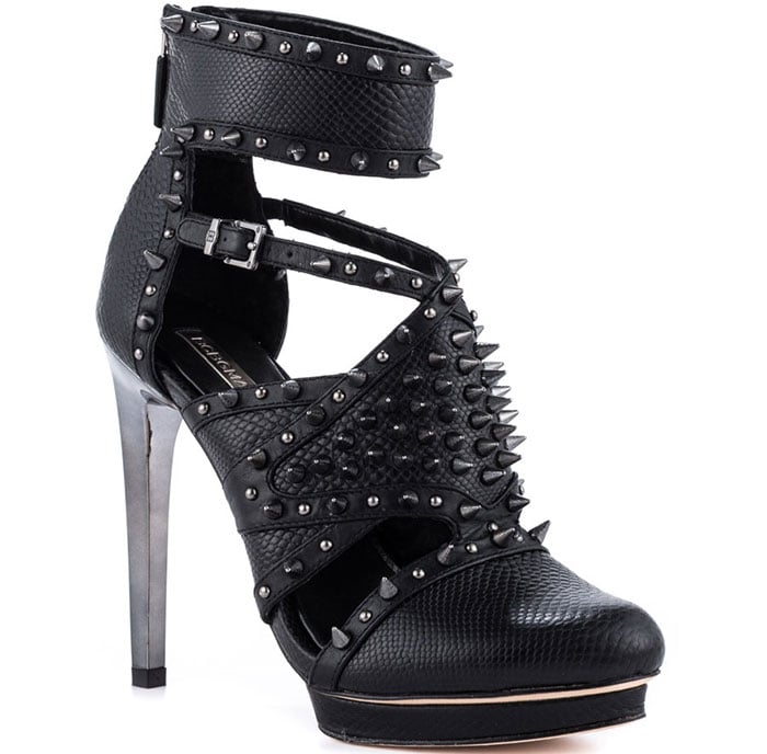 BCBGMAXAZRIA “Hersh” spiked pumps in black leather, featuring studded straps, ankle cuffs, and towering metallic heels that bring edge and structure to an all-black look