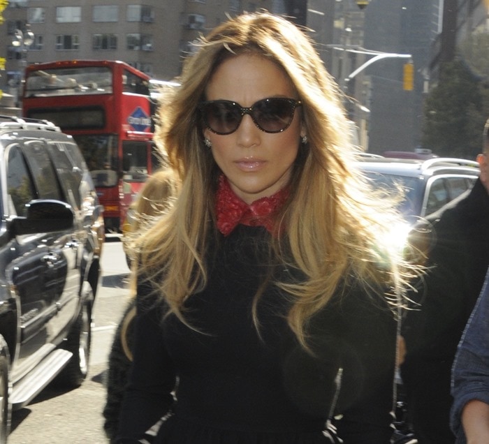 Jennifer Lopez shields her eyes behind oversized cat-eye sunglasses while stepping through Manhattan in a Valentino mini dress finished with a striking embellished red collar