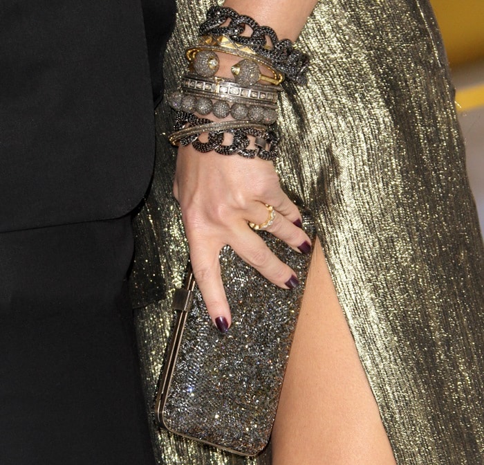 Jessica Simpson carries a glittering Ferragamo clutch and stacks Neil Lane bracelets with her metallic gold gown