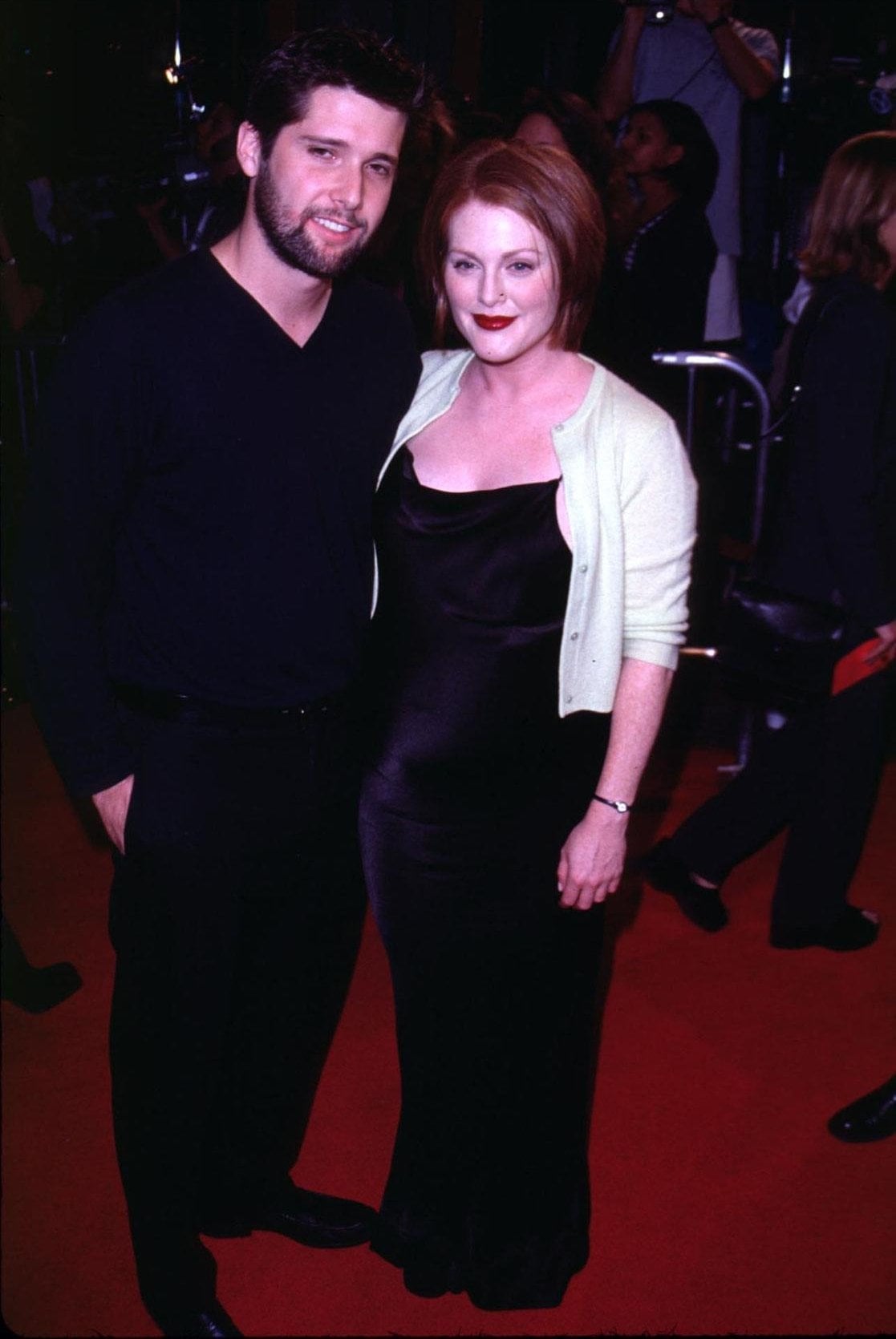 Julianne Moore radiates understated elegance in a silky black slip dress and pastel cardigan, posing with then-boyfriend Bart Freundlich at the Boogie Nights Los Angeles premiere at Mann Chinese Theatre on October 15, 1997