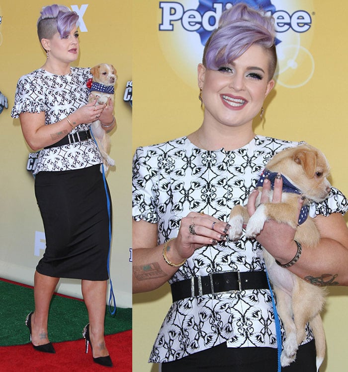 Kelly Osbourne softens her structured monochrome look with a playful touch, cradling an adorable puppy as she steps out in crystal-embellished René Caovilla pumps that add sparkle to her polished ensemble