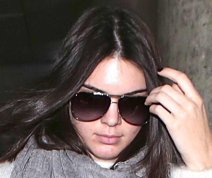 Kendall Jenner, seen at LAX, reveals her struggle with acne-prone skin, covered partially by sunglasses