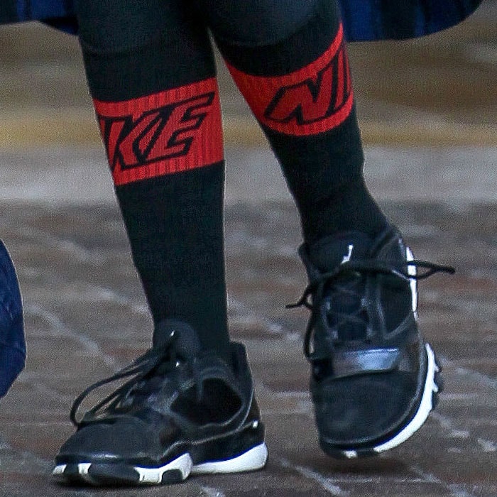 Close-up of Khloé Kardashian’s black Nike Air Jordans paired with bold red Nike socks, adding a streetwear twist to her post-event look