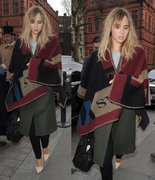 Suki Waterhouse is seen wearing a Burberry Prorsum color-block check blanket poncho over a green coat, paired with black skinny jeans and nude pointed-toe heels, accessorized with a black handbag
