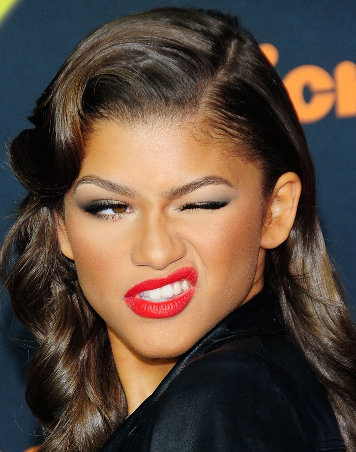 Zendaya adds a playful touch to the red carpet with a fierce wink and bold red lipstick