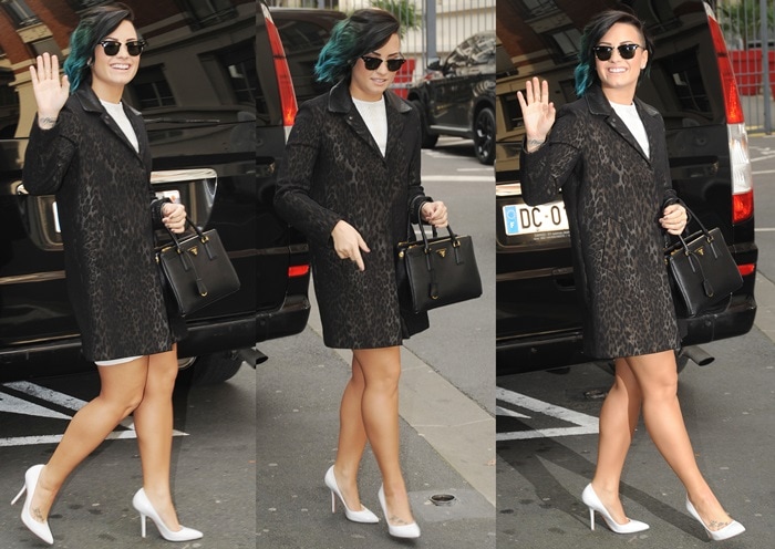 Demi Lovato wearing a Sandro leopard-print jacquard coat over a white dress