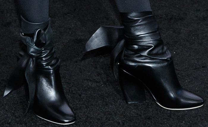 A closer look at Cameron Diaz's bold Dior ankle-tie boots, featuring sleek black leather, pointed toes, and statement wrap-around ribbon details