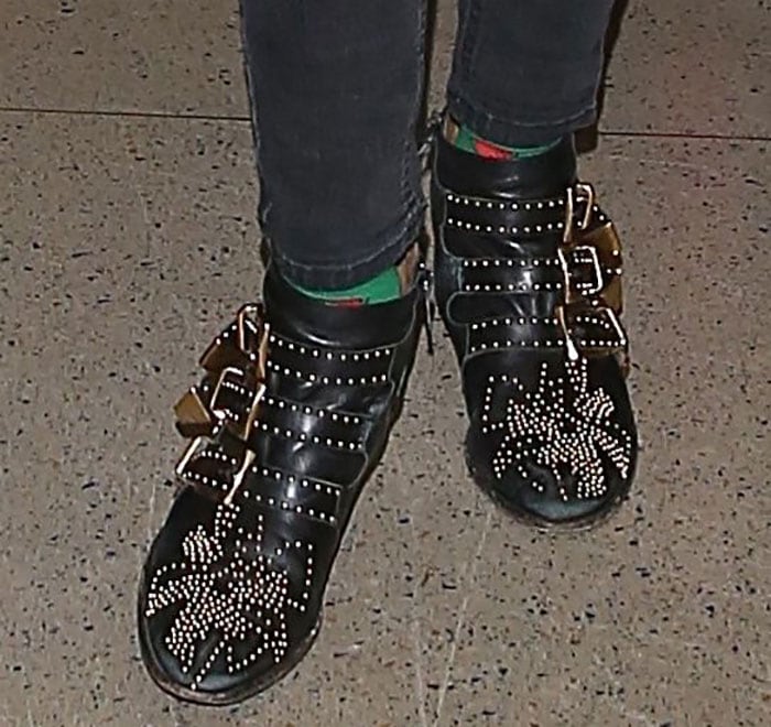 Close-up of Emma Roberts wearing black Chloé Susanna boots with gold-tone studs, buckled straps, and green socks