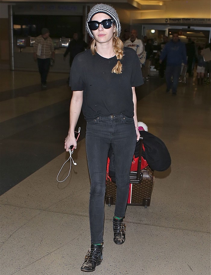 Emma Roberts wearing black Chloé Susanna studded ankle boots with skinny jeans and a striped beanie at LAX