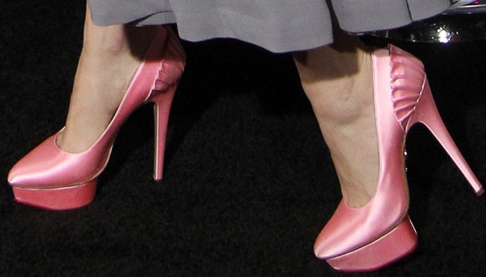 Her pink satin Charlotte Olympia “Paloma” platform pumps add a glamorous pop of color and perfectly tie together her soft, retro-inspired ensemble
