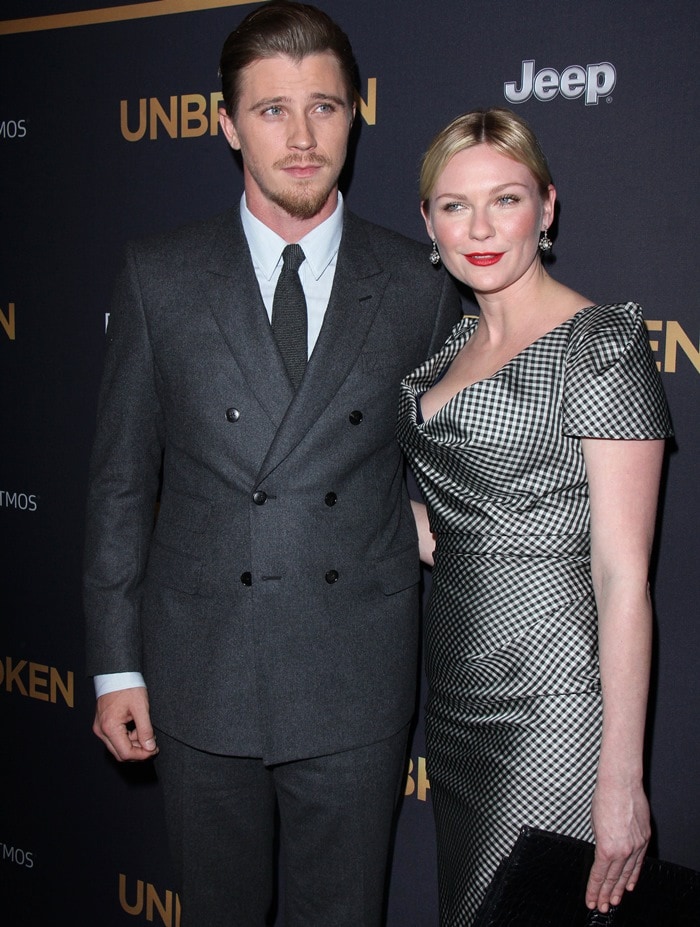 Kirsten Dunst stuns in a vintage-inspired gingham-print Vivienne Westwood dress, paired with a black clutch, as she accompanies Garrett Hedlund in a Gucci "Signoria" suit at the Unbroken premiere in Hollywood