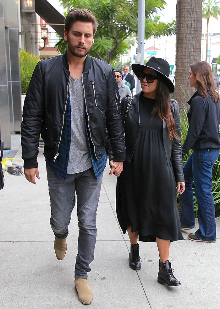 Kourtney Kardashian in a black maternity dress, leather biker jacket, wide-brim hat, and lace-up combat boots