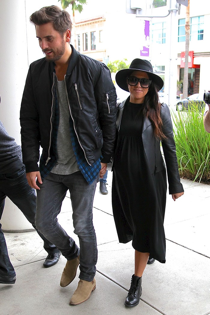 Scott Disick in gray jeans and tan suede boots walking with Kourtney Kardashian in black combat boots