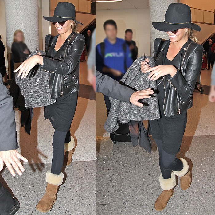 Chrissy Teigen sharing a joke with her companions while making her way through the paparazzi at the LAX Airport