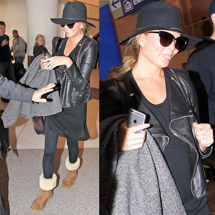 Chrissy Teigen showcases her chic airport style in an all-black ensemble, pairing cozy UGG boots with a leather jacket and Janessa Leone fedora for effortless travel comfort at LAX Airport in Los Angeles