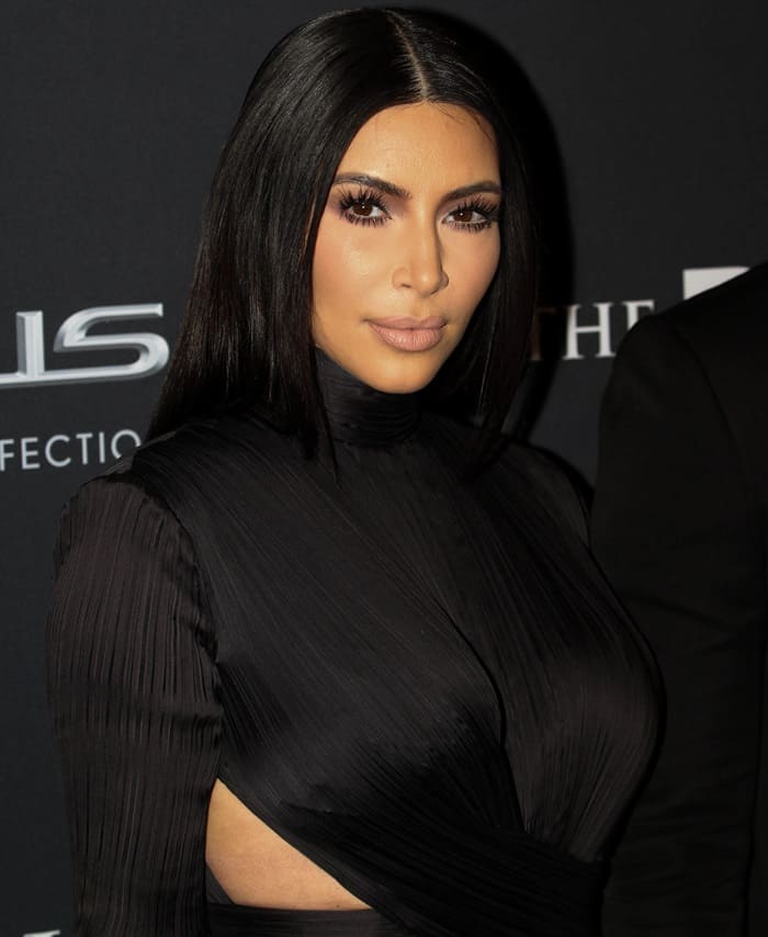Kim Kardashian styled her sleek black Balmain gown with minimalist makeup, nude lipstick, smoky eyes, and sleek, straight hair parted in the middle