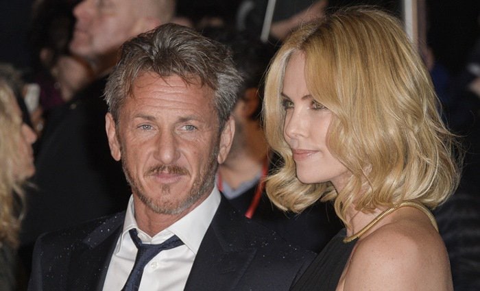 Charlize Theron and Sean Penn pose together, with Charlize in a chic black dress and Sean in a sharp suit