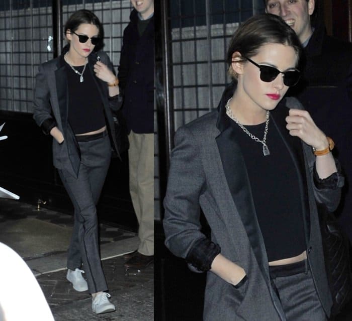Kristen Stewart exudes confidence in a sleek gray suit, paired with a black crop top, stylish sunglasses, and her signature "Punk Lock" necklace