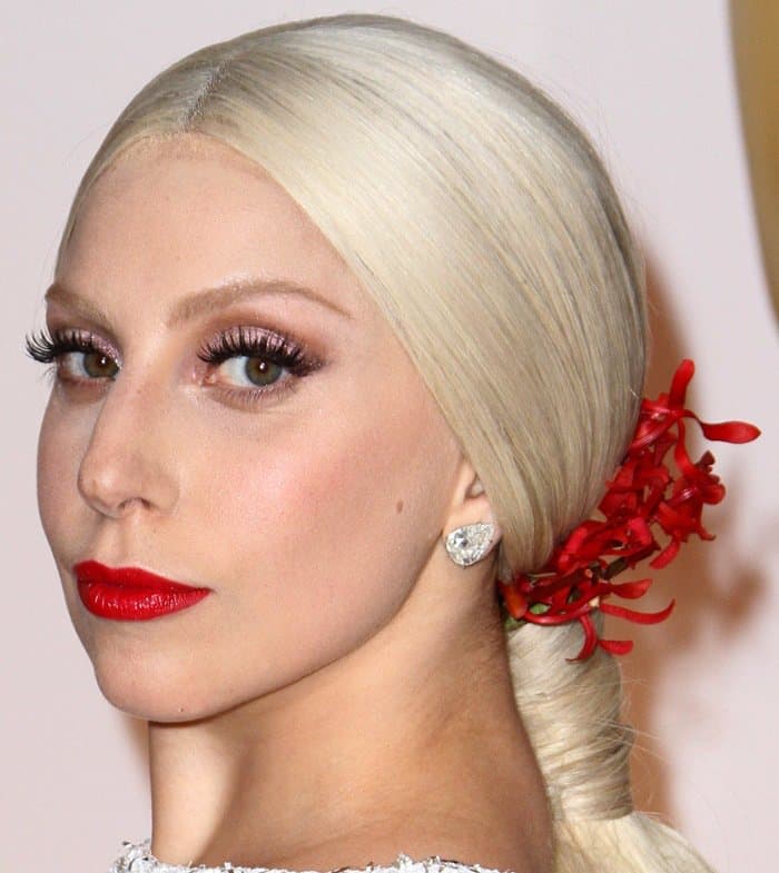 Lady Gaga styled her look with sleek, platinum blonde hair adorned with red orchid blooms and finished with bold red lipstick and diamond earrings