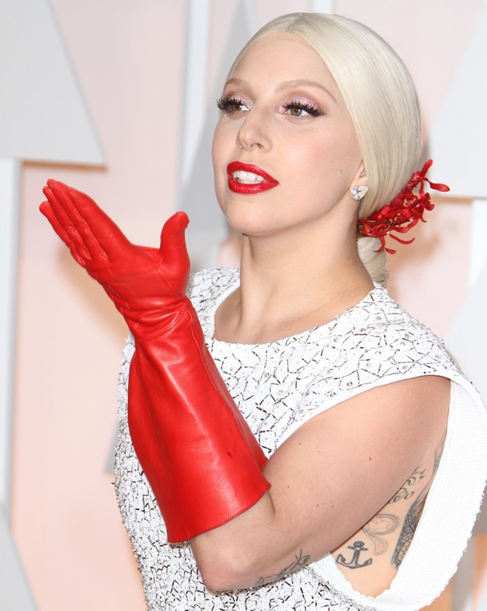 Lady Gaga accentuated her red carpet look with bold, elbow-length red leather gloves, adding a striking contrast to her white textured dress