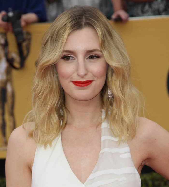 Laura Carmichael styled her look with a white dress featuring sheer details, paired with bold red lipstick and loose waves for a glamorous and modern appearance