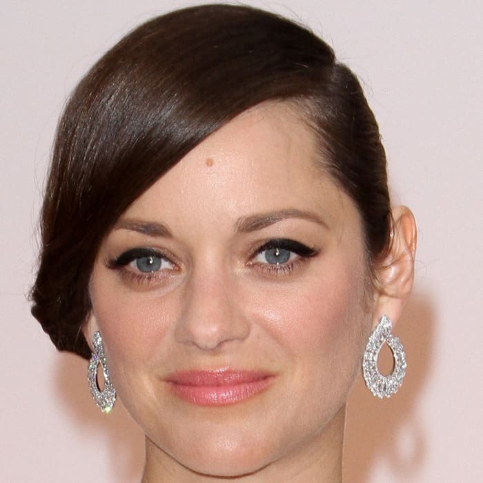Marion Cotillard styled her elegant ensemble with sparkling teardrop earrings and a sleek side-swept hairstyle, accentuating her classic beauty