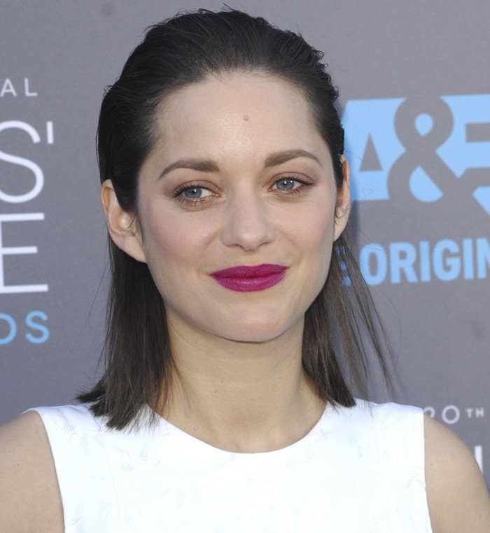 Marion Cotillard styled her look with a white dress and bold fuchsia lipstick, with her hair swept back for a chic and understated elegance