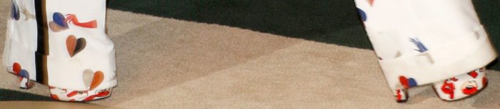 A close-up reveals the dramatic height and sculptural proportions of the platforms, emphasizing how the shoes command attention even beneath wide-leg pants