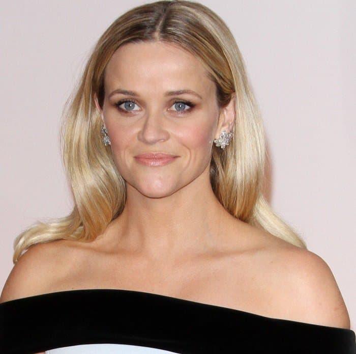 Reese Witherspoon’s polished beauty look—soft waves, diamond studs, and natural makeup—complemented the modern elegance of her off-the-shoulder gown