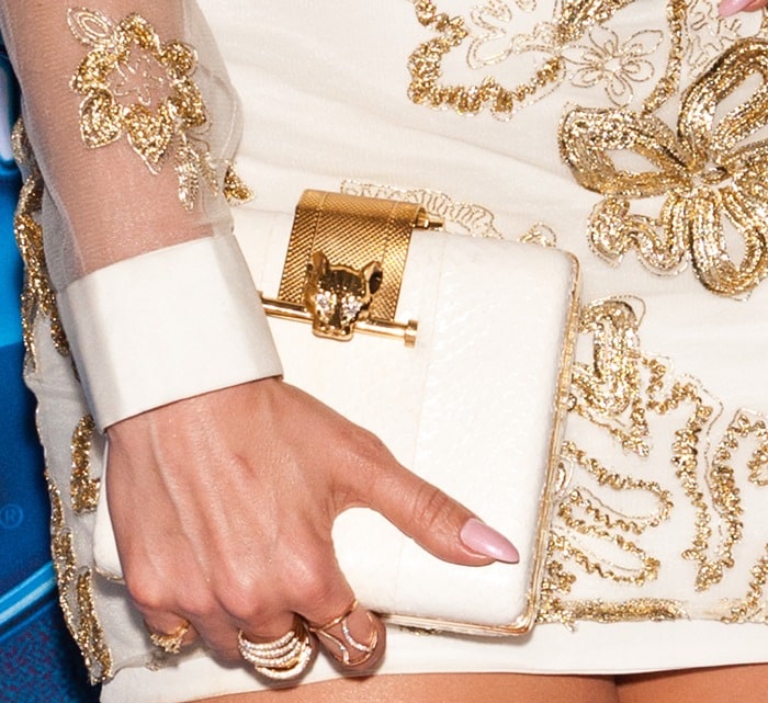 Jennifer Lopez carries a gold-embellished clutch as she shows off her pink manicure and gold rings