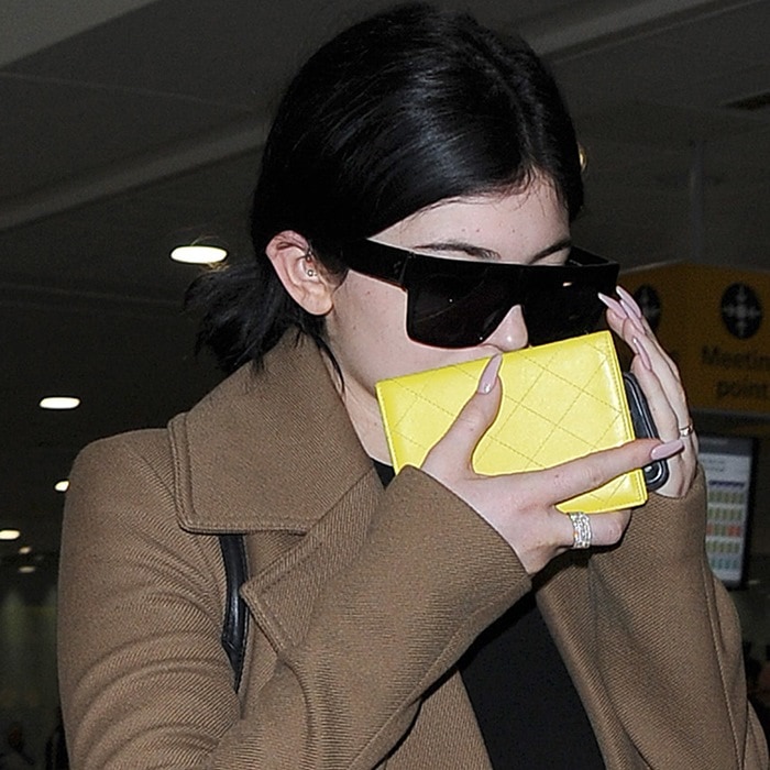 She playfully covered her face with a yellow wallet, adding a bright, unexpected accent to her neutral travel palette