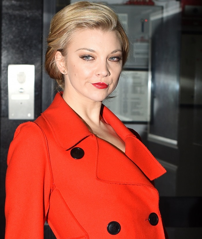 Natalie Dormer radiates confidence in a vibrant red Dior coat, featuring a sharp double-breasted design, bold black buttons, and a structured silhouette