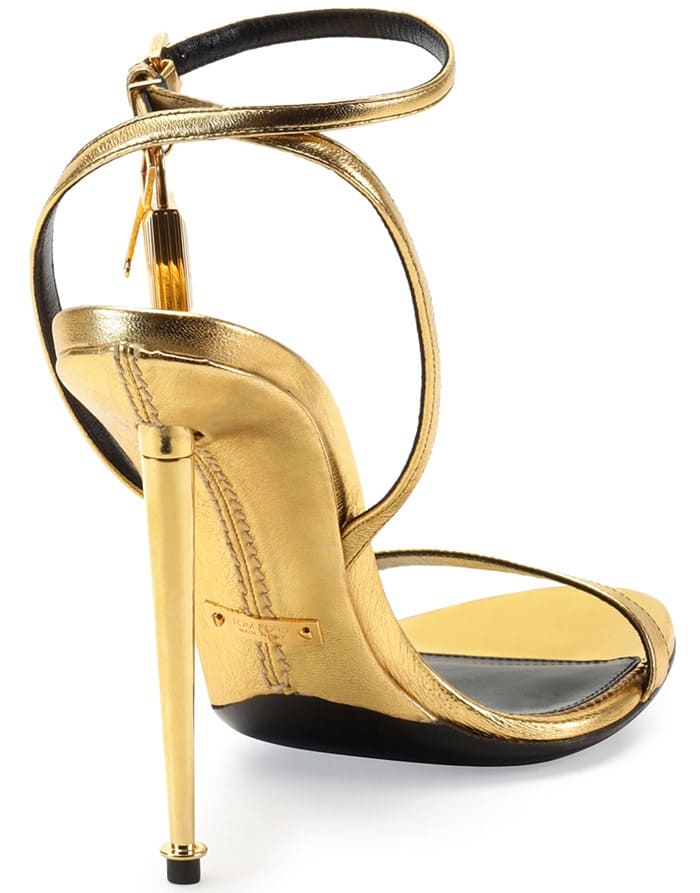 Tom Ford’s metallic ankle-lock sandals combined minimalist strappy styling with sculptural gold stiletto heels, turning a classic barely-there silhouette into a dramatic statement shoe