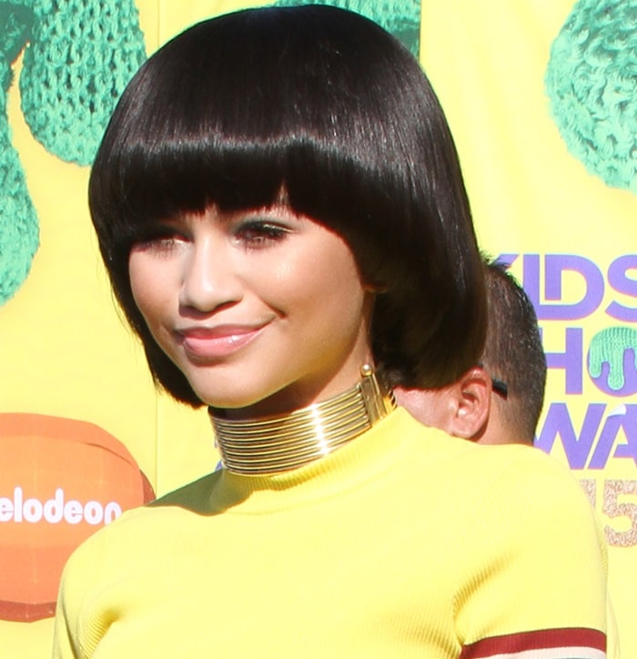 Zendaya debuts a sculptural bob haircut with a gold Masai-inspired choker at the 2015 Kids’ Choice Awards, complementing her striped DKNY look with sleek, mod-inspired glamour
