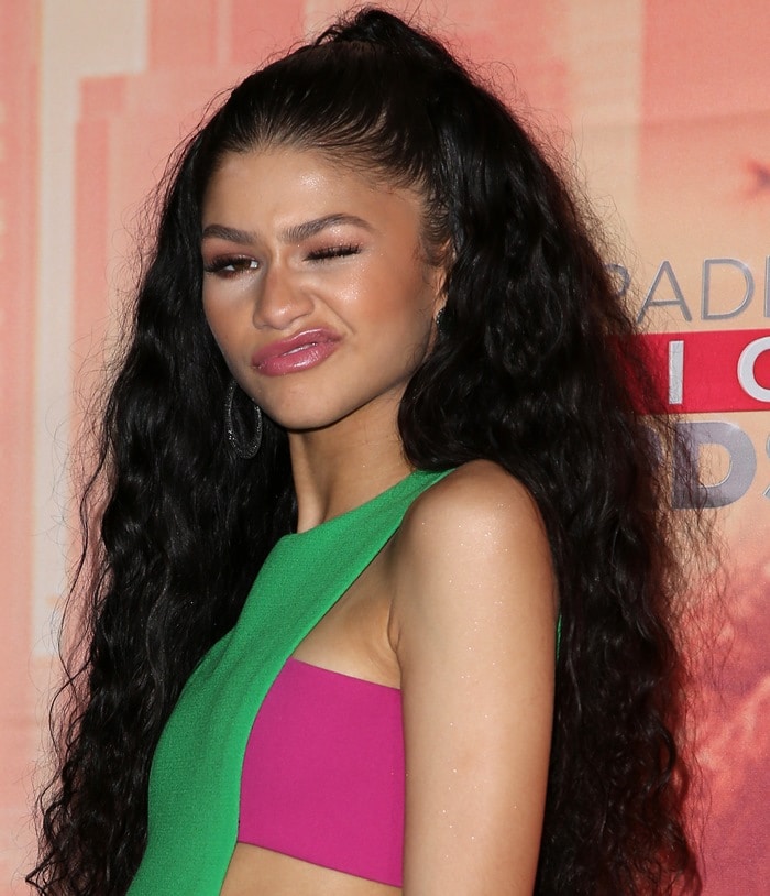 Zendaya pulls a funny face on the iHeartRadio Music Awards red carpet, showing off her flawless glam makeup and glossy pink lips