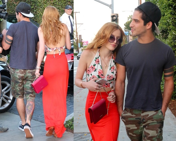 Bella Thorne steps out with Tyler Posey, sporting a floral halter top, a vibrant red maxi skirt, and a chic red purse, while Tyler keeps it casual in a t-shirt and camo shorts