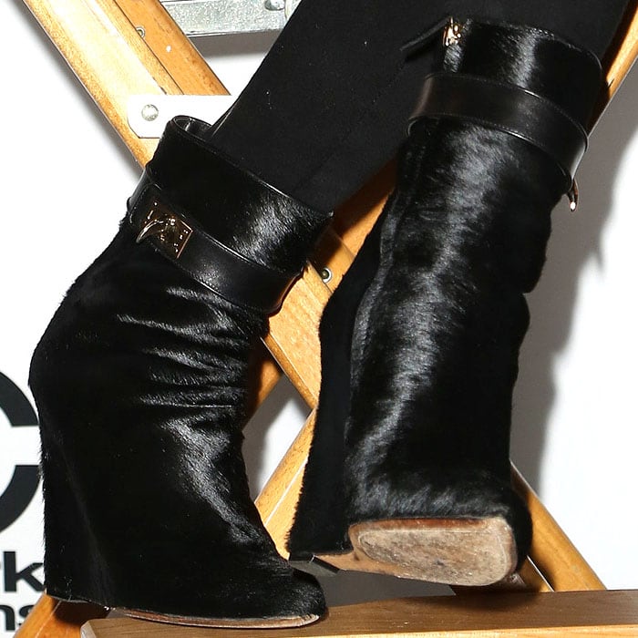 Close up on Chrissy Teigen’s edgy footwear choice: black Givenchy pony-hair sharktooth ankle boots with a slouched silhouette and angular heel, adding texture and attitude to her all-black press-conference look