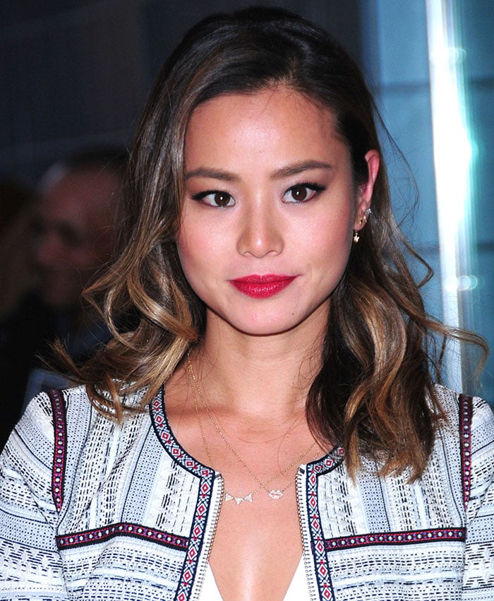 Jamie Chung kept her beauty look fresh and modern with soft waves, winged eyeliner, and a bold red lip, finishing the look with delicate layered gold necklaces and dainty stud earrings