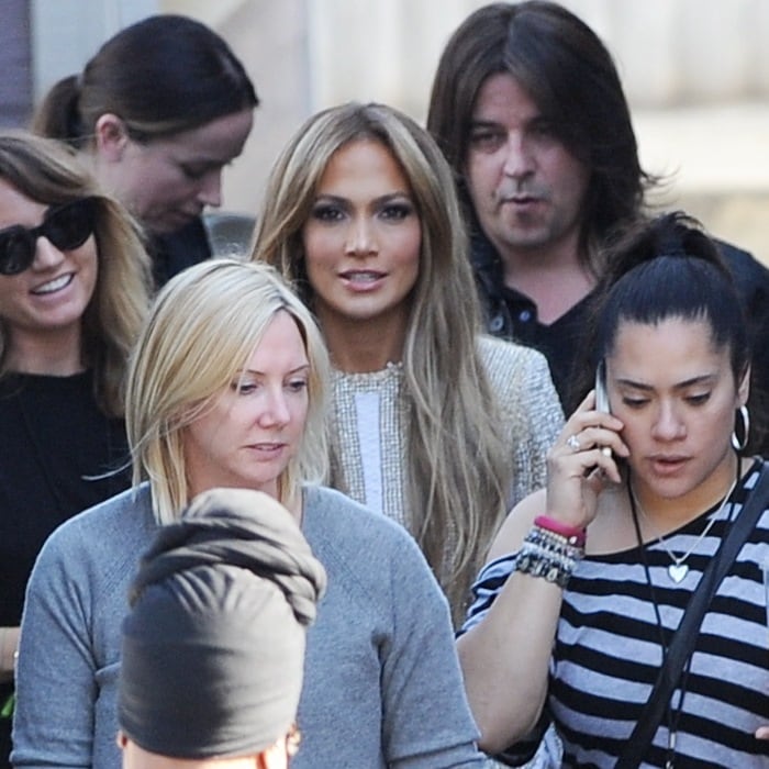 Jennifer Lopez surrounded by her team while heading to American Idol in Los Angeles, showcasing her chic style in a beige beaded mini dress by Nicolas Jebran
