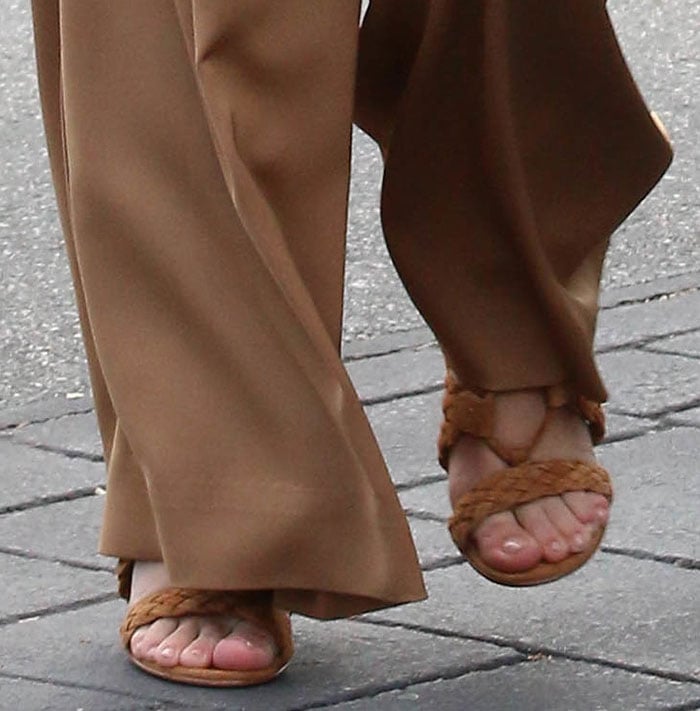 Kourtney Kardashian steps out in Gianvito Rossi's "Jimi" braided sandals, effortlessly complementing her wide-leg trousers with a chic and neutral-toned ensemble