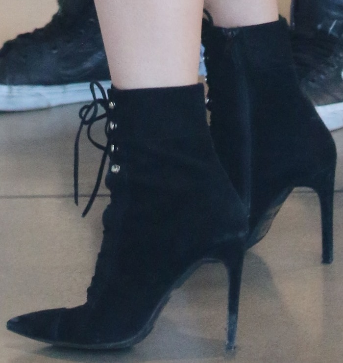 A close-up shot of Kylie Jenner's black suede "Elphaba" boots by Jeffrey Campbell, featuring a pointed toe, stiletto heel, and lace-up design with silver hardware