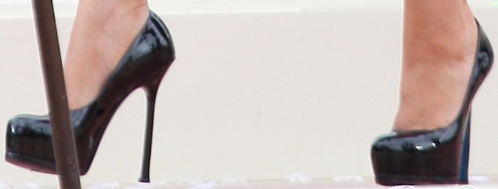 A close-up of Christina Aguilera’s glossy black Yves Saint Laurent Tribute double-platform pumps highlights their towering stiletto heels and dramatic curved platforms