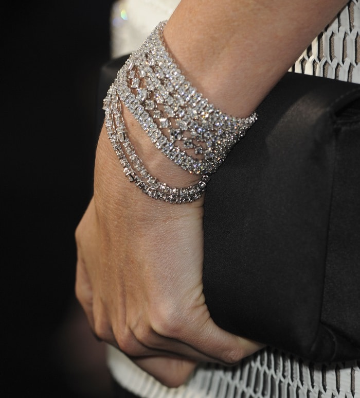 Charlize Theron showing off a black clutch and glittering Harry Winston bracelets