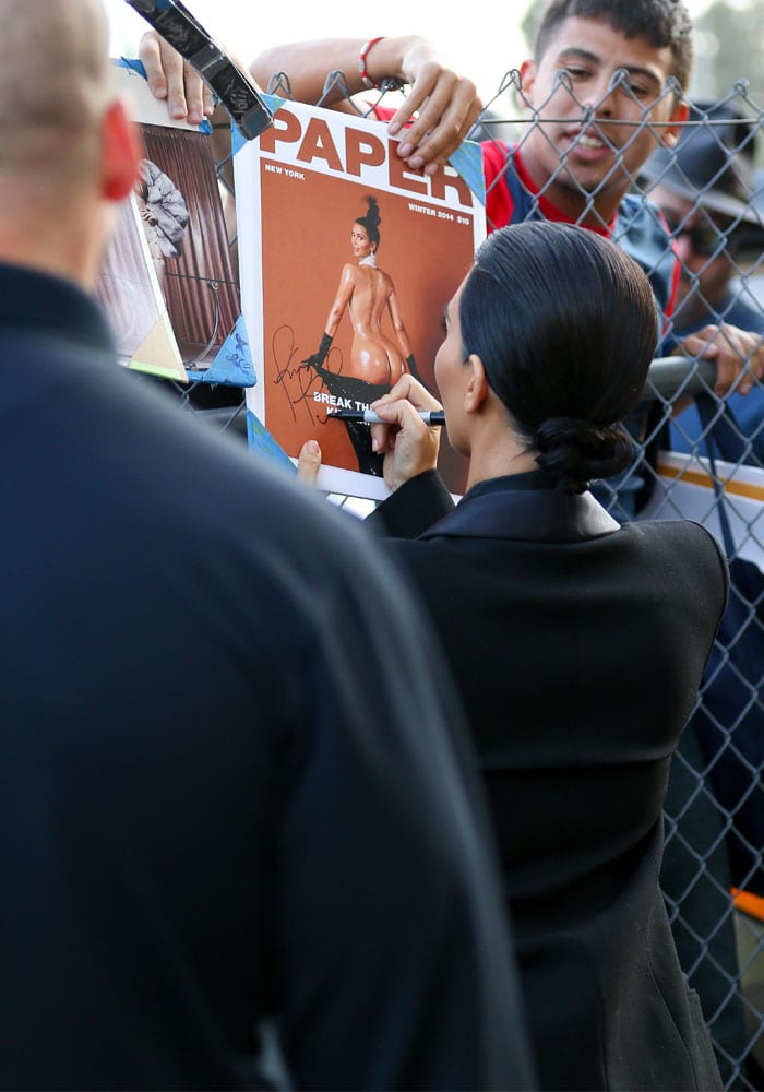 Kim Kardashian signs a copy of her provocative "Break the Internet" cover for Paper magazine