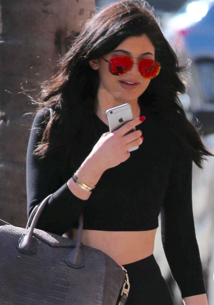 Kylie Jenner keeps it sleek in a black American Apparel stretch crop top, styling it with Victoria Beckham Classic Victoria sunglasses, a Givenchy croc-embossed Antigona bag, and a hint of gold from her Audemars Piguet Royal Oak watch and Cartier bracelet