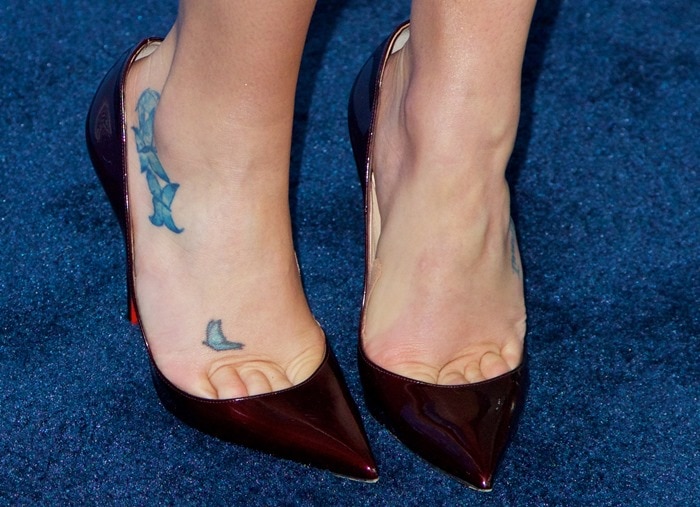 Lea Michele’s Louboutin pumps frame her bluebird and “Imagine” foot tattoos, spotlighting the star’s signature ink against the sharply pointed toe box