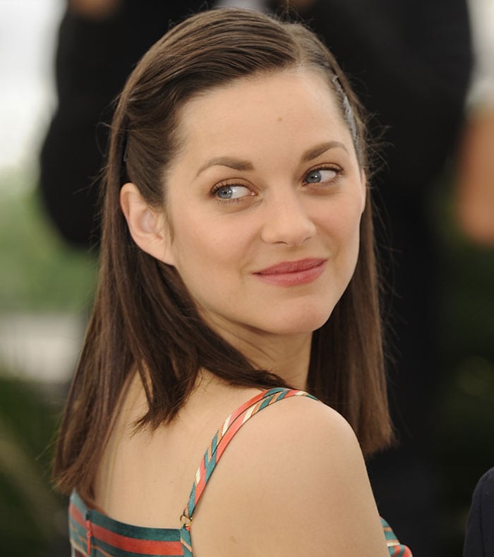 Marion Cotillard's natural beauty shines through with her side-parted hair, subtly bronzed eyelids, and a fresh pink lip shade at the Cannes Film Festival photo call
