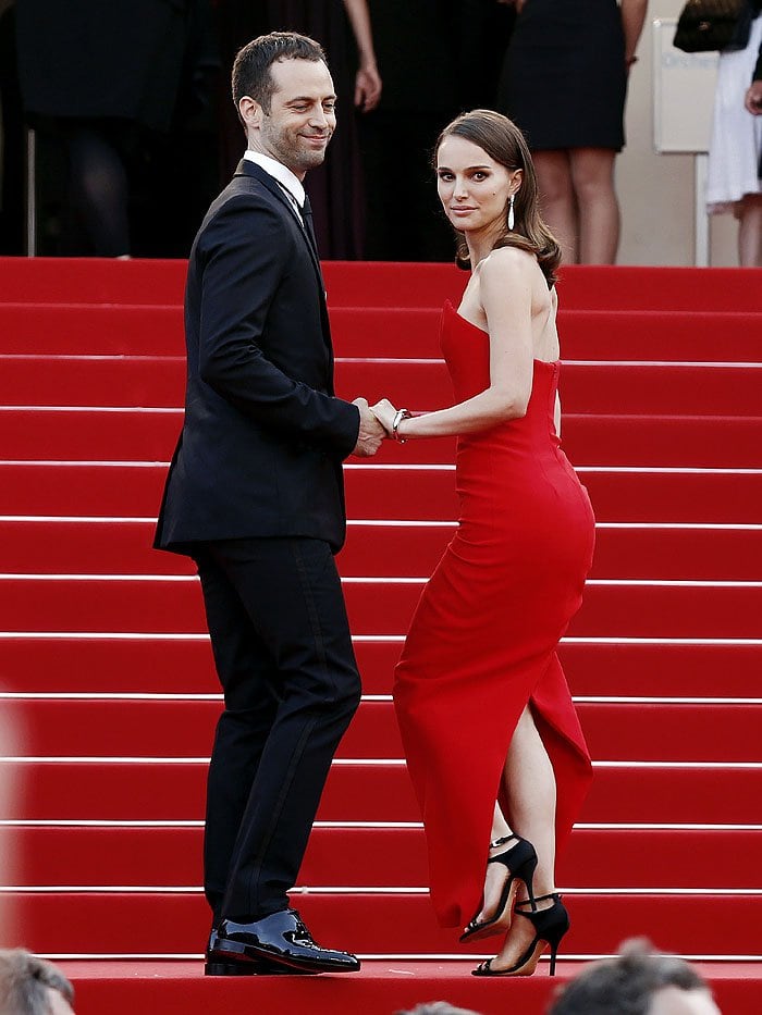 Benjamin Millepied and Natalie Portman ascend the iconic red stairs at the Cannes Film Festival, with Natalie showcasing her black satin sandals and red gown