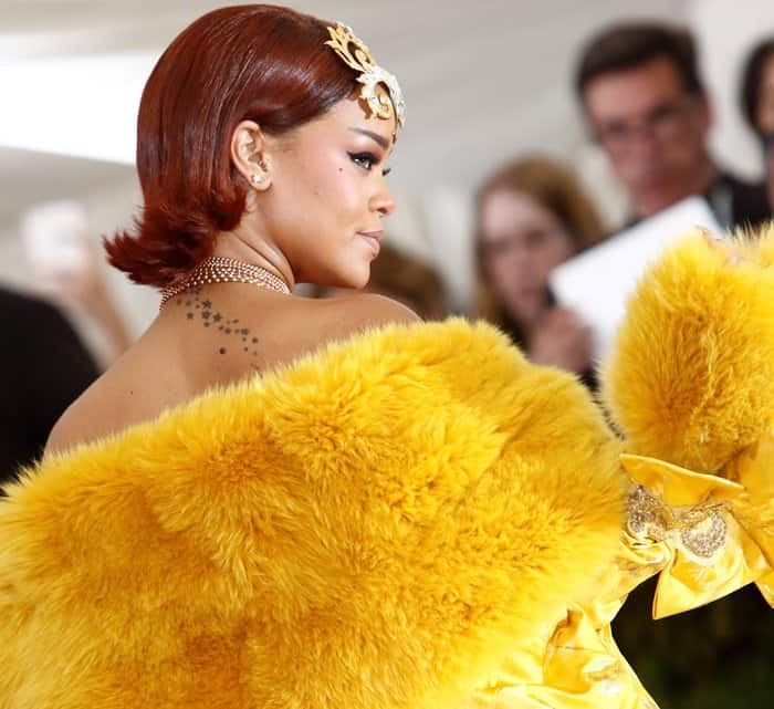 Rihanna exudes elegance in a stunning yellow fur-trimmed gown by Guo Pei, complemented by a jeweled crown and layered necklace, at the 2015 Met Gala